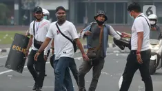 Polisi berpakaian kaus putih mengamankan seseorang yang dicurigai terlibat kericuhan di kawasan Tugu Tani, Jakarta, Selasa (13/10/2020). Sejumlah pemuda diamankan polisi karena dicurigai terlibat kericuhan di kawasan Tugu Tani. (Liputan6.com/Helmi Fithriansyah)