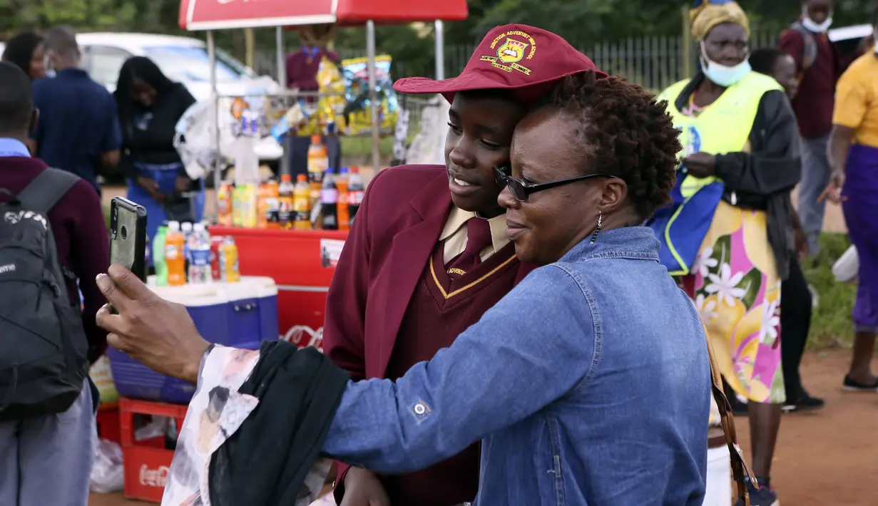 Orang tua berfoto dengan putrinya sebelum naik bus menuju sekolah di Harare, Minggu (6/2/2022). Sekolah-sekolah di Zimbabwe dibuka kembali pada 7 Februari setelah penundaan selama berminggu-minggu dalam mengizinkan siswa kembali menyusul meningkatnya infeksi COVID-19. (AP Photo/Tsvangirayi Mukwazhi)