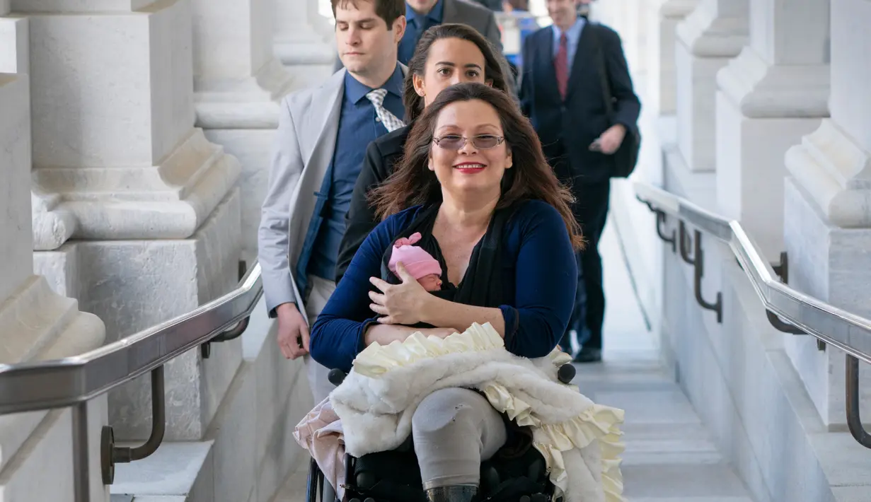 Senator negara bagian Illinois, Tammy Duckworth membawa bayinya ke ruangan kongres Gedung Capitol Hill, Washington DC, AS, Kamis (19/4). Duckworth (50) menggendong sang putri dalam pengambilan suara untuk nominasi pengurus NASA. (AP/J. Scott Applewhite)