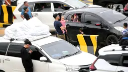 Pemudik keluar dari kendaraannya untuk beristirahat saat berada di Pelabuhan Merak, Banten, Jumat (29/4/2022). Banyak pemudik yang memanfaatkan waktu sebelum masuk kapal dengan beristirahat di area dermaga setelah mereka terjebak macet hingga berjam-jam. (Liputan6.com/Angga Yuniar)