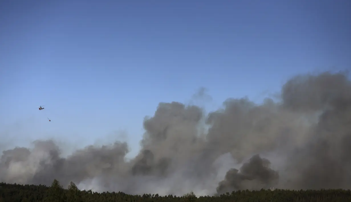 Helikopter pemadam kebakaran terbang di atas kebakaran hutan di distrik Landal Caldas da Rainha di Portugal, Rabu (17/8/2022). Namun, para pejabat memperingatkan perkiraan gelombang panas baru untuk daerah tersebut dapat memperumit tugas tersebut. (AP Photo/Joao Henriques)