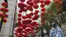 Orang-orang berjalan melewati dekorasi untuk merayakan Tahun Baru Imlek di Hong Kong, Minggu (30/1/2022). Tahun Baru China atau Imlek jatuh pada 1 Februari (AP Photo/Vincent Yu)