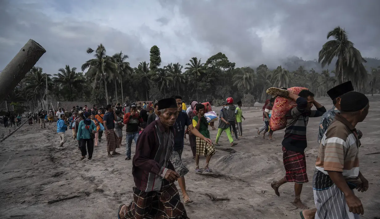 Warga menyelamatkan barang-barang mereka di daerah yang tertutup abu vulkanik setelah letusan gunung Semeru di desa Sumber Wuluh di Lumajang, Jawa Timur, Minggu (5/12/2021). BNPB menyatakan, korban meninggal akibat Gunung Semeru meletus mencapai 13 orang. (AFP /Juni Kriswanto)