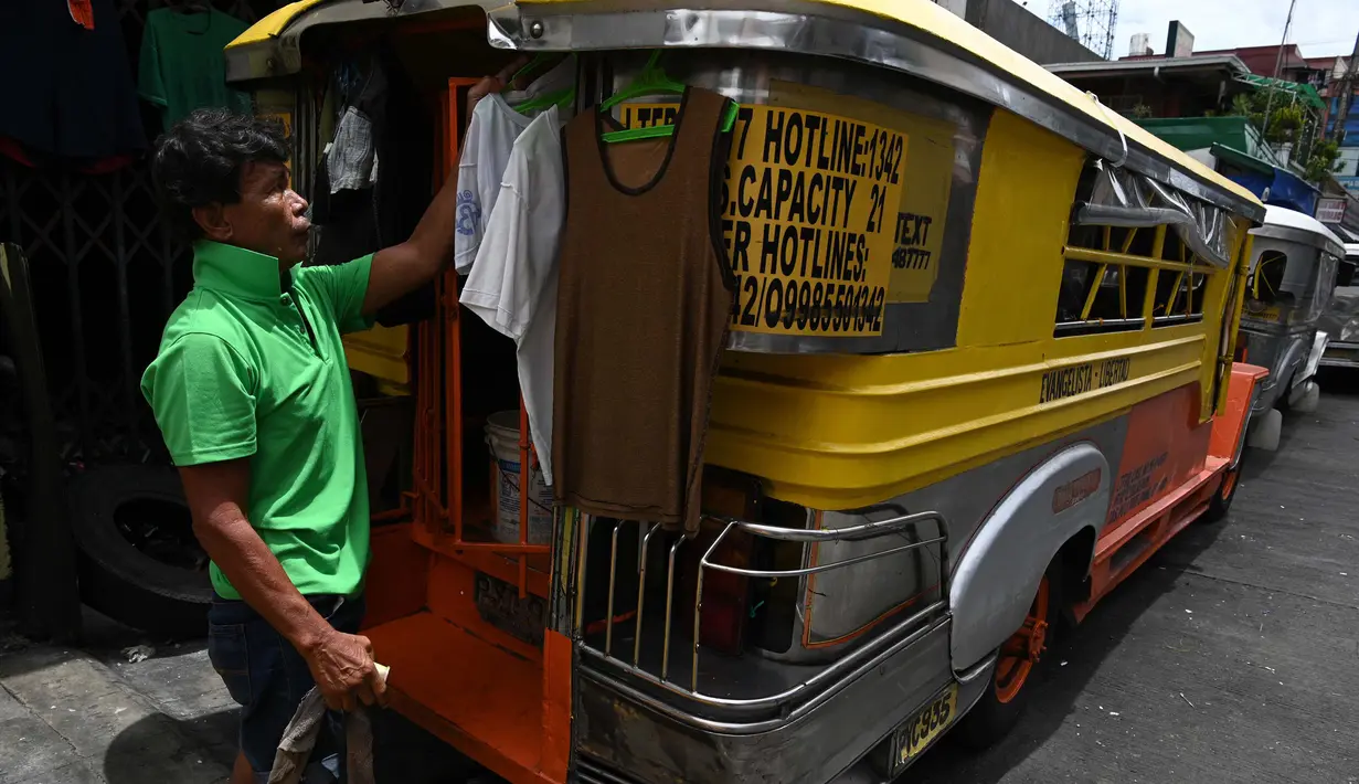 Pengemudi menggantung baju di jeepney miliknya yang berfungsi sebagai rumah sementara di sepanjang jalan di Manila, 12 Agustus 2020. Angkutan ikonik di Filipina itu belum dapat mengangkut penumpang sejak Maret akibat lockdown Covid-19 yang membuat jutaan orang kehilangan pekerjaan. (Ted ALJIBE/AFP)