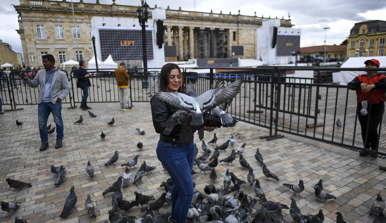 Seorang perempuan memberi makan burung merpati di Bolivar Square di mana panggung untuk upacara pelantikan Presiden terpilih Kolombia Gustavo Petro sedang didirikan, di Bogota pada 5 Agustus 2022. Gustavo Petro akan mulai menjabat pada 7 Agustus 2022 mendatang. (Juan BARRETO / AFP)