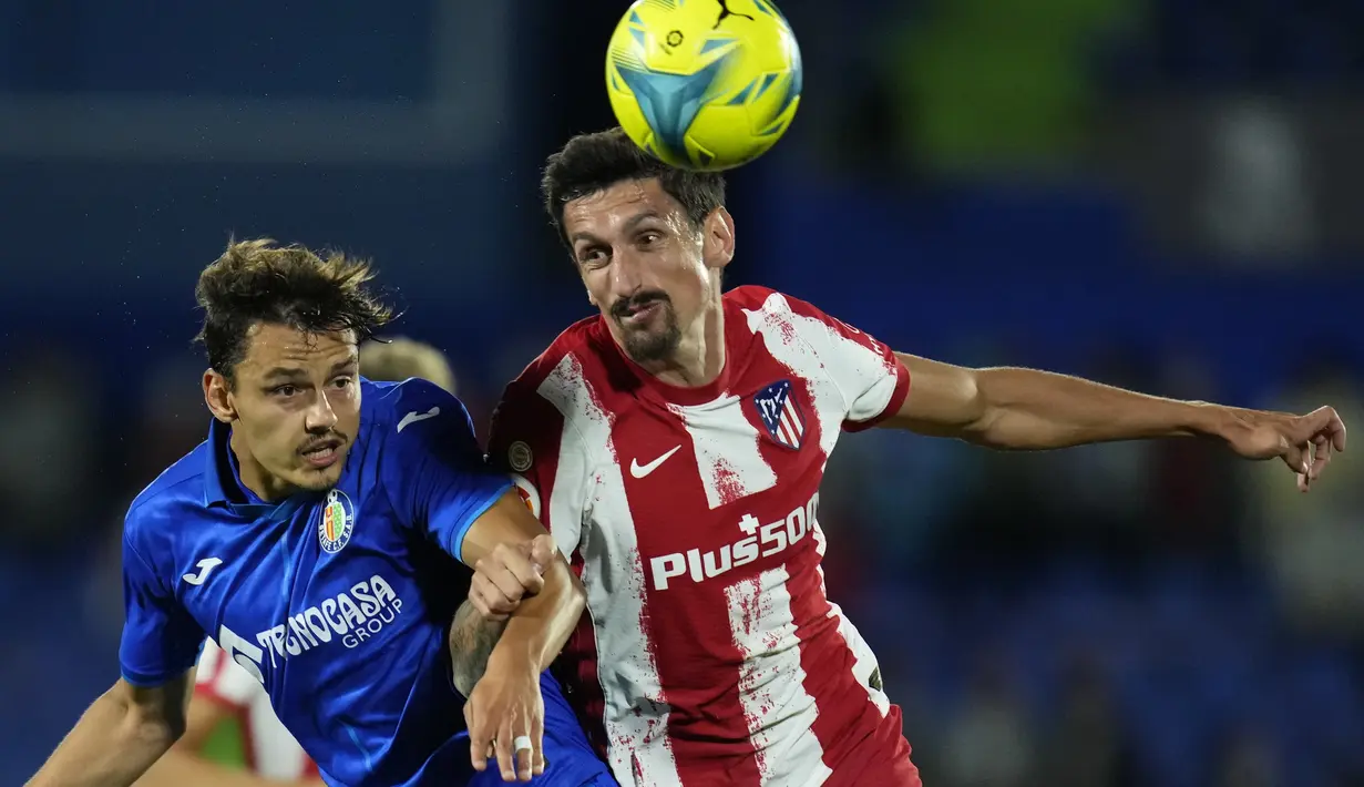 Penyerang Getafe, Enes Unal berebut bola dengan bek Atletico Madrid, Stefan Savic pada laga pekan keenam Liga Spanyol di Stadion Coliseum Alfonso Perez, Rabu (22/9/2021) dini hari WIB. Luis Suarez memborong dua gol saat Atletico Madrid mengalahkan Getafe 2-1. (AP Photo/Manu Fernandez)