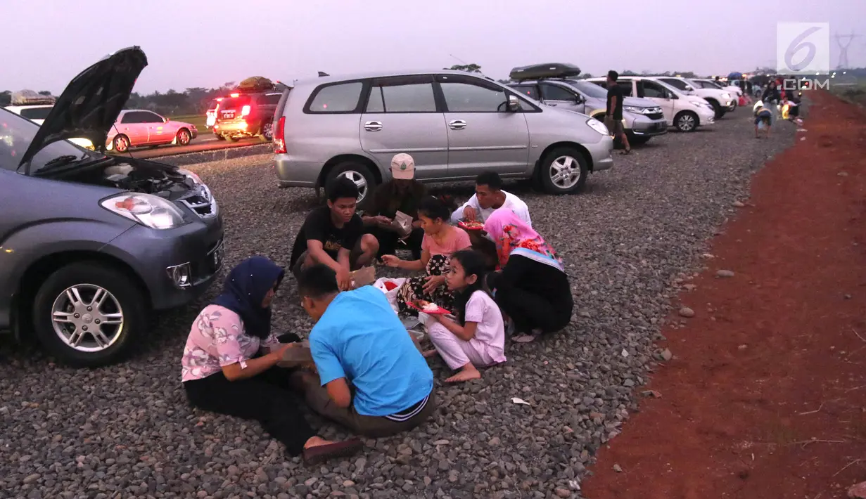Pemudik menyantap hidangan berbuka puasa di pinggir Tol Fungsional Pemalang-Batang, Jawa Tengah, Minggu (10/6). Sambil berbuka mereka juga mendinginkan kendaraannya. (Liputan6.com/Arya Manggala)