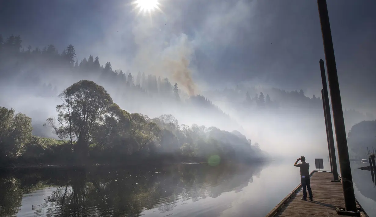 Asap terlihat di atas Sungai Siuslaw dekat Mapleton saat The Sweet Creek Milepost 2 Fire menyala di lereng bukit yang menghadap ke kota, Oregon, Amerika Serikat, 1 September 2020. (Chris Pietsch/The Register-Guard via AP)