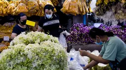 Pelanggan melihat-lihat bunga menjelang Loy Krathong di pasar bunga Pak Khlong Talat, Bangkok, Kamis (18/11/2021). Bulan November ini Thailand akan mengadakan festival Loy Krathong di mana warga akan menghanyutkan keranjang berisi bunga dan lilin di sungai, kolam atau danau. (Jack TAYLOR/AFP)