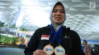 Atlet panjat tebing putri Indonesia, Aries Susanti Rahayumenunjukkan medali usai penyambutan di Bandara Soetta, Tangerang, Rabu (16/5). Aries berhasil mengalahkan Elena Timofeeva (Rusia) dengan waktu 7,51 detik. (Liputan6.com/Helmi Fithriansyah)