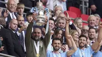 Pelatih Manchester City, Pep Guardiola (kiri) mengangkat trofi Piala FA setelah berhasil membawa Manchester City keluar sebagai juara dalam pertandingan final FA Cup 2022/2023 melawan Manchester United yang berlangsung di Wembley, Sabtu (3/6/2023) WIB. (AP Photo/Dave Thompson)