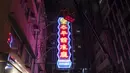 Pekerja menghapus tanda neon yang digantung di gedung restoran Tai Ping Koon sejak 1964 di Hong Kong, Minggu, 6 Agustus 2023. Dulunya ada di mana-mana di jalan-jalan Hong Kong, tanda neon ikonik kota itu menghilang karena pengetatan peraturan pemerintah. (AP Photo/Louise Delmotte)