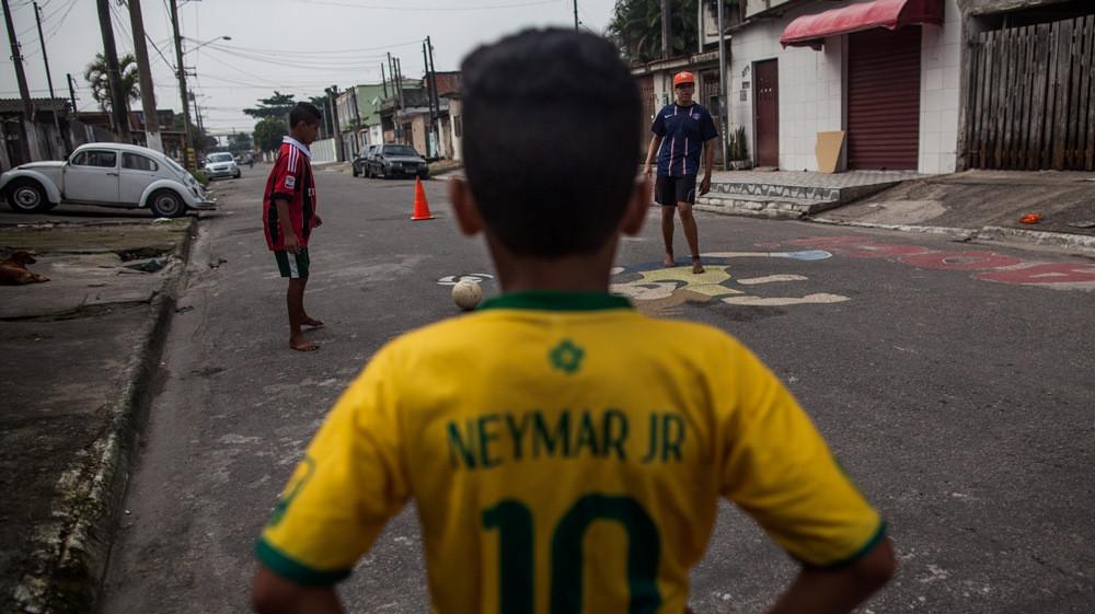 Anak-anak bermain sepak bola di jalan Garden Gloria, Santos, Brasil. (The Guardian). 