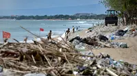 Pekerja menggunakan alat berat membersihkan sampah dan sampah plastik saat pembersihan pantai Kuta dekat Denpasar di pulau wisata Bali (6/1/2021). (AFP/Sonny Tumbelaka)
