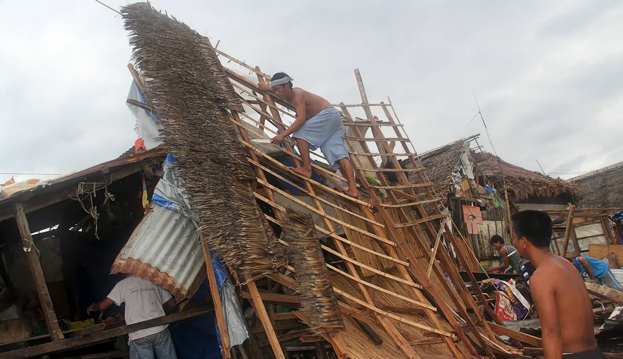 Warga merapihkan puing puing di desa Pigcale pesisir pantai yang terkena Topan Melor, di kota Legazpi, provinsi Albay, Filipina (15/12). Dasyat Topan Melor menyebabkan banjir, badai 800.000 orang dievakuasi dari Filipina tengah. (REUTERS/Rhaydz Barcia)