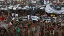 Ratusan orang dari suku asli Brasil menggelar aksi di luar gedung Kongres Nasional di Brasilia, Brasil (25/4). Mereka mengenakan pakaian tradisional dan membawa replika peti mati saat menggelar aksinya. (AP Photo/Eraldo Peres)