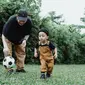 Ilustrasi ayah dan anak. (Photo by Ketut Subiyanto: https://www.pexels.com/photo/man-in-black-t-shirt-playing-with-boy-in-brown-overall-and-soccer-ball-4933837/)