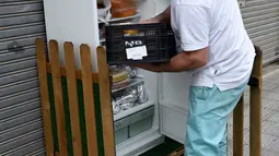 Pemilik restoran menyimpan makanan ke dalam kulkas di pinggir trotoar Galdakao, utara Spanyol, Senin (31/5). Warga setempat dan restoran bisa menaruh sisa makanan atau makanan tak terpakai ke dalam kulkas, dibanding harus membuangnya. (Ander GILLENEA/AFP)