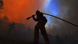Seorang petugas pemadam kebakaran menarik selang sambil melindungi rumah di sepanjang Crystal Springs Road saat memerangi Glass Fire di St. Helena, California pada 27 September 2020. (Jose Carlos Fajardo / Bay Area News Group via AP)