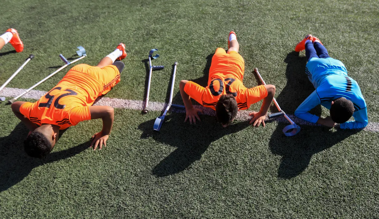 Anak-anak Palestina yang diamputasi melakukan pemanasan dalam sesi pelatihan sepak bola, yang diatur oleh Komite Palang Merah Internasional (ICRC) setelah pembatasan penyakit coronavirus (COVID-19) mereda, di Deir al-Balah di Jalur Gaza tengah (14/7/2020). (AFP/Mahmud Hams)
