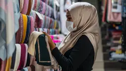 Pekerja mengenakan masker sebagai tindakan pencegahan penyebaran Covid-19 merapikan kerudung menjelang Idul Fitri yang menandai berakhirnya bulan suci Ramadan di Kuala Lumpur (13/5/2020). (AFP/Mohd Rasfan)