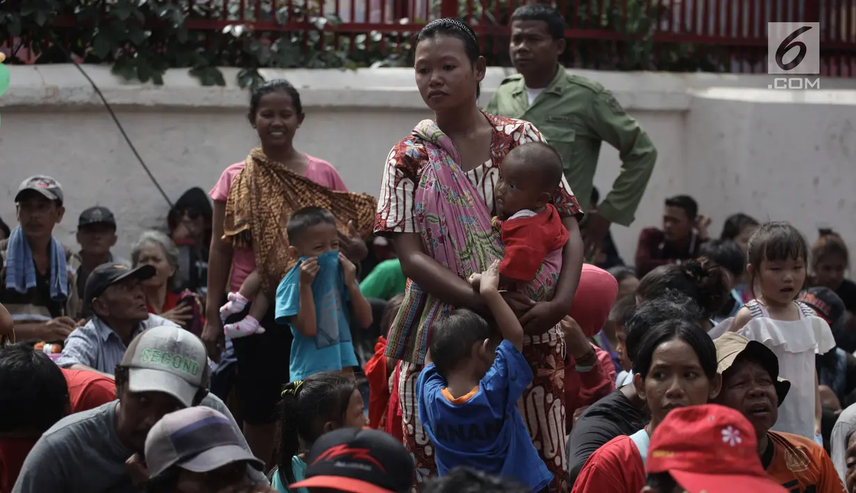Seorang pengemis menggendong anaknya menunggu sedekah Imlek di depan Wihara Dharma Bhakti, Petak Sembilan, Jakarta, Jumat (16/2). Mereka selalu hadir setiap Imlek untuk menerima angpao dari jemaah yang datang bersembahyang. (Liputan6.com/Arya Manggala)