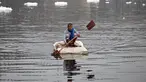 Seorang pria mendayung rakitnya sambil mengumpulkan bahan-bahan daur ulang dekat potongan busa tercemar yang mengambang di Sungai Yamuna, New Delhi, India, 26 Desember 2021. Lapisan busa beracun melapisi sungai yang dianggap suci oleh umat Hindu, Sungai Yamuna. (Sajjad HUSSAIN/AFP)