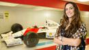 Bianca Senna, kemenakan Ayrton Senna yang juga direktur branding Institut Ayrton Senna berpose di depan mobil F1 yang pernah dipakai Ayrton Senna di Institut Ayrton Senna di Sao Paulo, Brasil. (AFP/Alexandre Schneider)