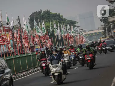 Pengendara melintas di dekat bendera parpol yang terpasang di pembatas jalan kawasan Tebet, Jakarta, Selasa (25/7/2023). (Liputan6.com/Faizal Fanani)