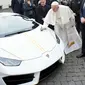 Paus Fransiskus memberikan tanda tangan di kap mesin Lamborghini Huracan di Vatikan, Rabu (15/11). Perusahaan Lamborghini memberi hadiah mobil Lamborghini Huracan berwarna putih untuk Paus Fransiskus. (L'Osservatore Romano/Pool Photo via AP)