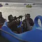 Sejumlah pasukan Taliban saat menaiki perahu kayuh di Danau Qargha di sebuah pekan raya di Kabul barat (28/9/2021). Sambil membawa senjata laras panjang sambil berjaga, mereka mengayuh perahu bebek memutari danau. (AFP/Wakil Kohsar)
