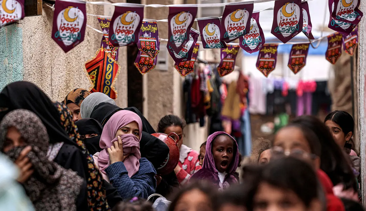 Pengungsi Palestina bersama anak-anak harus mengantre untuk mendapatkan makanan berbuka puasa. (SAID KHATIB/AFP)