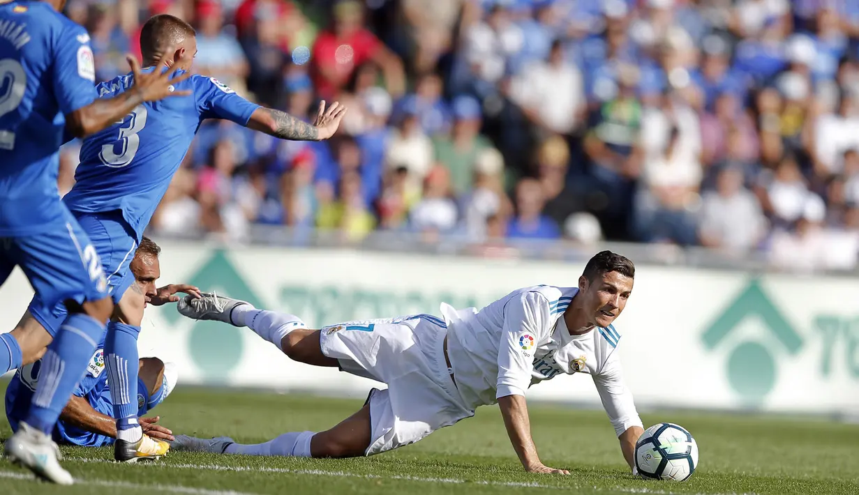 Striker Real Madrid, Cristiano Ronaldo, terjatuh saat pertandingan melawan Getafe pada laga La Liga Spanyol Stadion Coliseum Alfonso Perez, Sabtu (14/10/2017). Real Madrid menang 2-1 atas Getafe. (AP/Paul White)