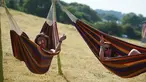 Dua wanita bersantai di tempat tidur gantung saat menghadiri Festival Musik Glastonbury di Worthy Farm, di Somerset, Inggris, (22/6). Festival Glastonbury merupakan festival musik paling populer di dunia. (AFP Photo/Oli Scarff)