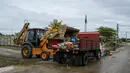 Sebuah ekskavator mengangkut puing-puing ke truk setelah air banjir surut di Mentakab, negara bagian Pahang Malaysia (11/1/2020). Tiga sungai di negara bagian itu - Sungai Lepar, Sungai Lipis dan Sungai Lembing - telah melewati tingkat bahaya. (AFP/Mohd Rasfan)