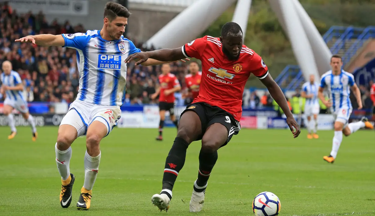 Bek Huddersfield, Christopher Schindler berusaha merebut bola dari striker Manchester United Romelu Lukaku saat pertandingan Liga Inggris di stadion John Smith di Huddersfield (21/10). (AFP Photo/Lindsey Parnaby)