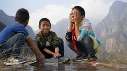 Sejumlah anak mencuci muka saat sampai di atas tebing Desa Atuleer, Tiongkok, Rabu (19/11). Sebelumnya, selama belasan tahun warga hanya menggunakan ranting pohon sebagai tangga untuk akses menuju kaki gunung. (REUTERS)