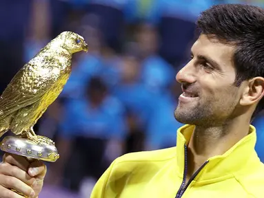 Petenis Serbia, Novak Djokovic, memegang piala usai menjadi pemenang tunggal putra Qatar Open di Doha, Minggu (10/1/2016). Pada laga final dirinya mengalahkan Rafael Nadal. (Reuters/Naseem Zeitoon)