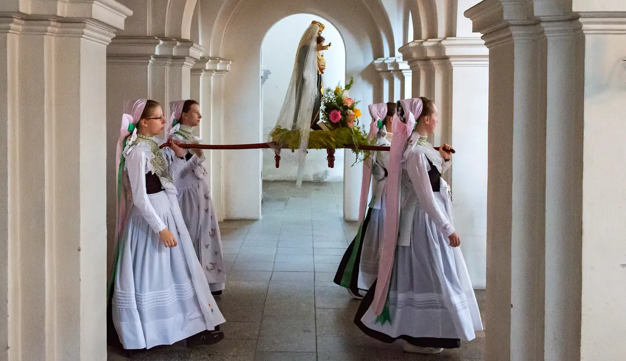 Sejumlah wanita berpakaian tradisional Sorbs membawa patung Bunda Maria saat menggelar ritual Whit Monday di Rosenthal, Jerman, Senin (10/6/2019). Para wanita muda membawa patung Bunda Maria ke sebuah lapangan untuk melangsungkan misa terbuka. (AP Photo/Jens Meyer)