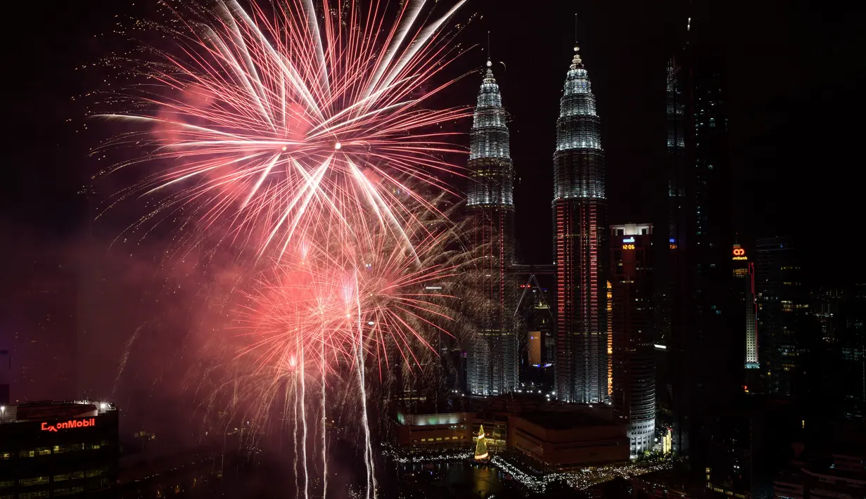 Kembang api menghiasi langit di dekat Menara Kembar Petronas Malaysia saat malam pergantian tahun di Kuala Lumpur, Malaysia. (01/1/2018). Menara Kembar Petronas menjadi salah satu spot para wisatawan menikmati malam tahun baru. (AFP Photo / Mohd Rasfan)