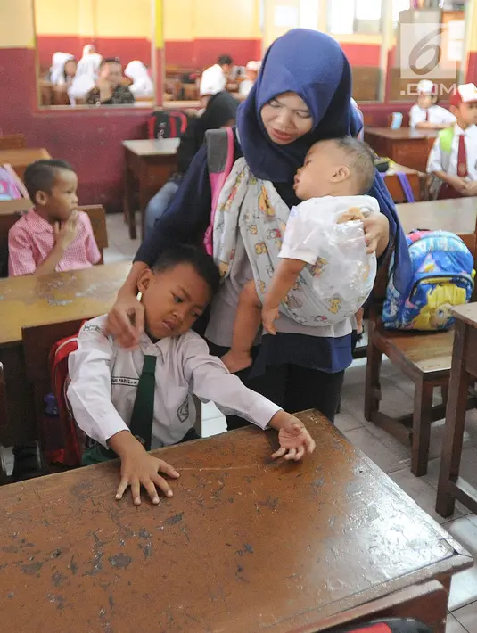 Seorang ibu menenangkan anaknya yang menangis saat hari pertama masuk sekolah di SDN Cinere 1, Depok, Jawa Barat, Senin (15/7/2019). Seluruh siswa SD, SMP dan SMA, pada hari ini mulai masuk sekolah pada tahun ajaran baru 2019/2020. (merdeka.com/Arie Basuki)