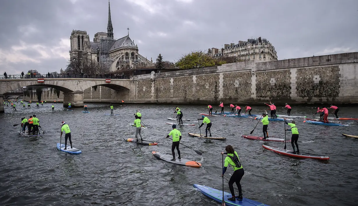Para peserta mengambil bagian dalam Nautic Paddle Race di Paris, Minggu (9/12). Sekitar 800 orang mengikuti lomba dayung sambil berdiri terbesar di dunia sejauh 11 km dengan pemandangan kota Paris. (Lucas BARIOULET/AFP)