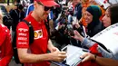 Pembalap Ferrari Sebastian Vettel menandatangani tanda tangan untuk para penggemar saat tiba di Sirkuit Melbourne Grand Prix di Melbourne, Jumat (15/3). GP Australia digelar di Sirkuit Melbourne Grand Prix, 15 hingga 17 Maret. (Reuters/Edgar Su)