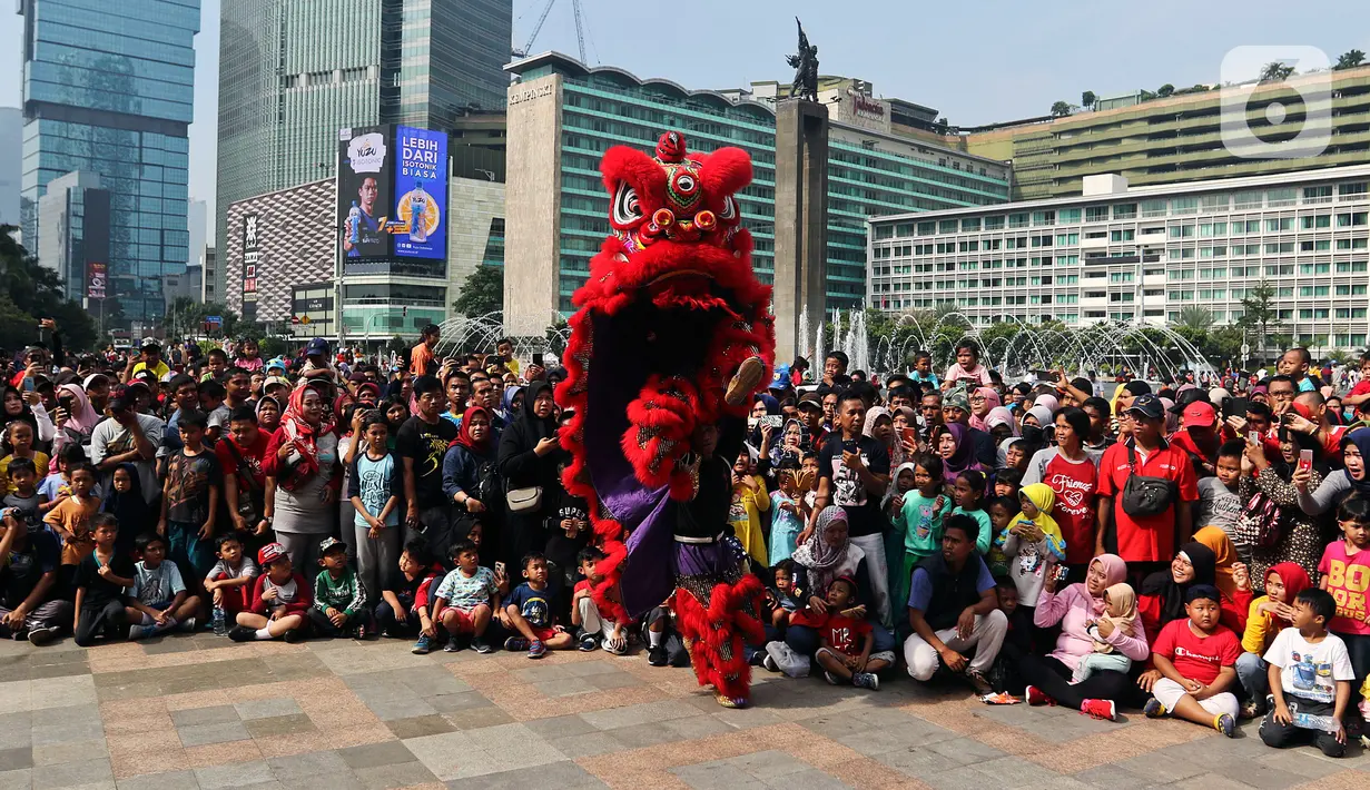 Warga menyaksikan pertunjukkan barongsai saat ajang car free day (CFD) di kawasan Bundaran HI Jakarta, Minggu (26/1/2020). Barongsai tersebut sengaja dihadirkan dalam rangka perayaan Imlek 2020 untuk menghibur para warga yang tengah mengikuti CFD. (Liputan6.com/Johan Tallo)