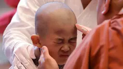 Reaksi bocah laki-laki saat rambutnya dicukur seorang biksu pada seremonial ulang tahun Buddha di kuil Jogye, Seoul, Rabu (2/5). Sepuluh anak terpilih mendapatkan pengalaman menjadi biksu dalam rangkaian acara peringatan hari lahir Buddha (AP/Lee Jin-man)