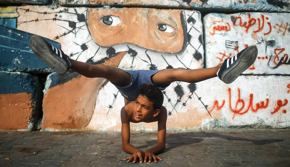 Yousef Al-Bahtini memperlihatkan keahlian akrobatiknya di pelabuhan Kota Gaza (20/9). Bocah Palestina ini siap memecahkan waktu tercepat rekor Guinness World Records dengan melakukan perjalanan 20 meter dalam kelenturan tubuh. (AFP Photo/Mohammed Abed)