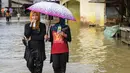 Warga melintasi jalan yang tergenang air di kawasan Rantau Panjang, Malaysia, Kamis (5/1). , Malaysia, Kamis (5/1). Hujan lebat dalam lima hari juga telah menyebabkan 101 sekolah ditutup. (AFP PHOTO / MOHD RASFAN)