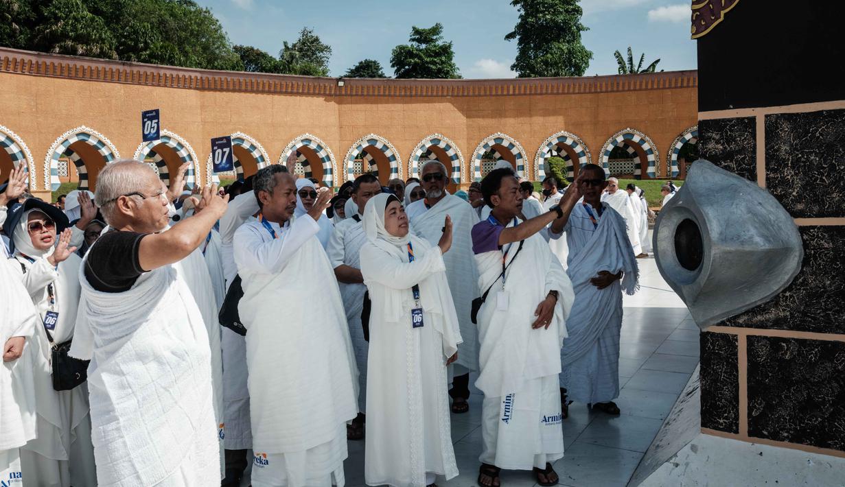 Para calon jemaah haji Indonesia melakukan ritual di depan replika Hajar al-Aswad (Batu Hitam) pada replika Ka'bah, di Pusat Pelatihan Manasik Al Mahmudah (AMTC), sebuah fasilitas pelatihan haji yang menampilkan replika situs-situs ziarah utama, di Tangerang Selatan pada 5 April 2026. (YASUYOSHI CHIBA/AFP)