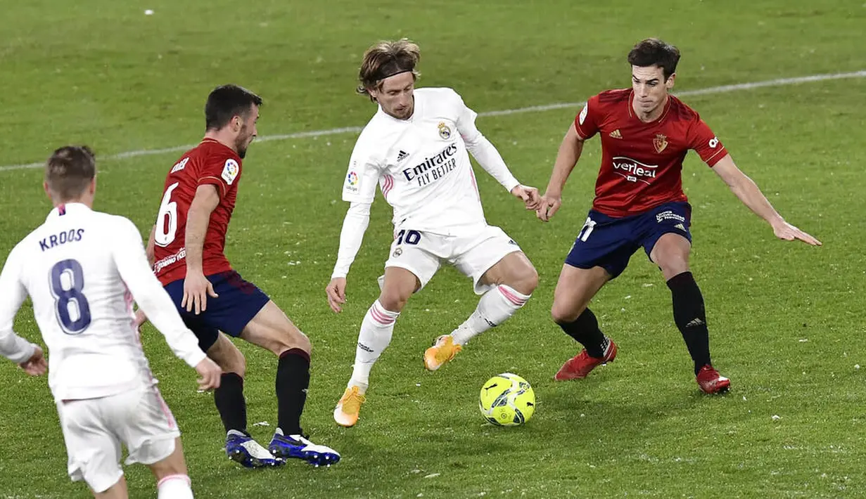 Gelandang Real Madrid, Luka Modric, berusaha melewati pemain Osasuna pada laga Liga Spanyol di Stadion El Sadar, Sabtu (9/1/2021). Kedua tim bermain imbang 0-0. (AP/Alvaro Barrientos)
