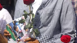 Seorang wanita mempersembahkan bunga mawar sebagai penghormatan kepada seorang guru yang tewas dalam protes kudeta militer di Yangon, Myanmar, Senin (1/3/2021). Para guru mencoba berkumpul lebih awal, tetapi polisi melemparkan granat kejut dan menyerbu untuk membubarkan protes. (AP Photo)